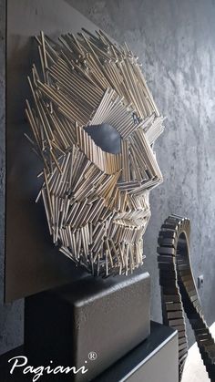 a sculpture made out of wooden sticks on top of a black table next to a gray wall