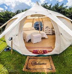 the inside of a tent set up on top of green grass with a bed in it