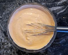 a bowl filled with batter and whisks on top of a marble countertop