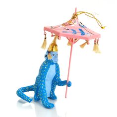 a blue monkey holding a pink umbrella with tassels on its head and legs