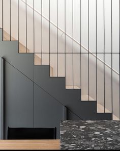 a stair case next to a wooden table with a black chair in front of it