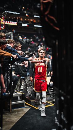 a man in a red and white uniform is walking down the court