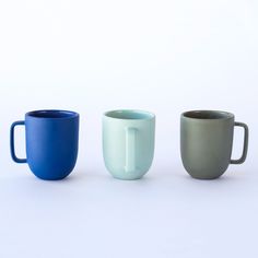 three different colored cups sitting next to each other on a white surface, one blue and one green