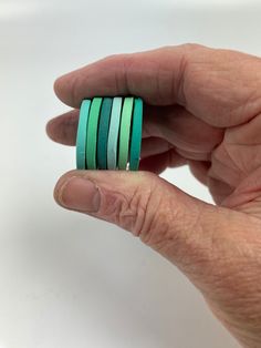 a person is holding three rings in their hand, one green and the other blue