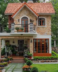 a small house with lots of plants and flowers in front of the windows on the second floor