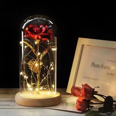 a glass jar with lights inside sitting on a table next to a framed photo and keychain