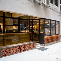 the entrance to a restaurant with people sitting at tables in the window and on the sidewalk