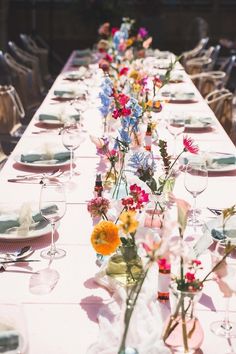 a long table with flowers and plates on it