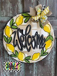 a door hanger with the word welcome painted on it and yellow lemons around it