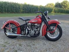 a red motorcycle parked on top of a gravel road