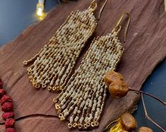 two pairs of beaded earrings sitting on top of a piece of cloth next to beads