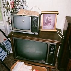 an old fashioned tv sitting on top of a wooden table next to a piano and other items