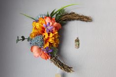 a bouquet of flowers is hanging on the wall next to a small piece of jewelry