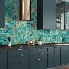 a kitchen with blue cabinets and green marble tiles on the backsplash, along with gold accents