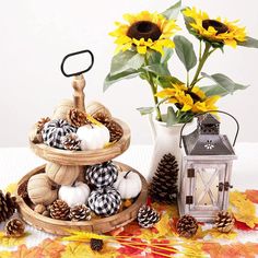 three tiered baskets filled with pumpkins and sunflowers next to a lantern