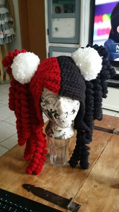 two knitted hats sitting on top of a wooden table next to a computer keyboard