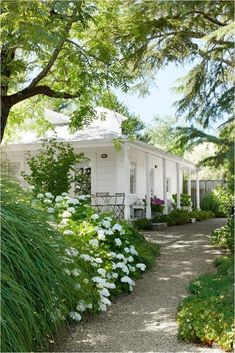 a white house surrounded by trees and flowers