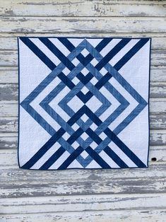 a blue and white quilt hanging on the side of a wooden building with wood planks