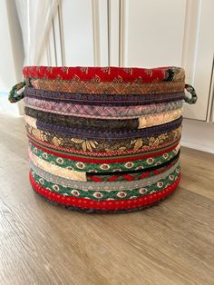 a stack of multicolored bracelets sitting on top of a wooden floor