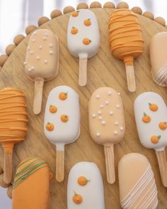 there are many popsicles on the wooden plate with oranges and white frosting