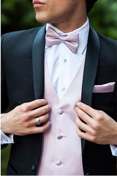 a man in a tuxedo adjusts his bow tie