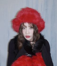 a woman wearing a red fur hat and black coat