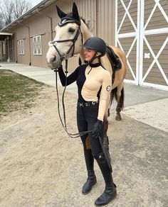 a woman standing next to a horse in front of a barn