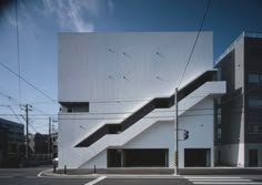 an empty street in front of a white building with stairs on the side of it