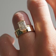 a close up of a person's hand wearing a gold ring with a diamond