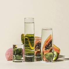 three glasses filled with different types of fruit and vegetables next to each other on a white surface