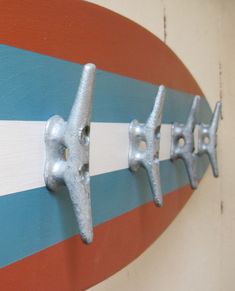 three metal hooks are mounted on the side of a surfboard that is painted red, white and blue