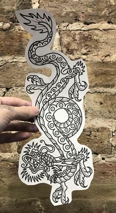 a hand holding up a sticker with an image of a dragon in the middle