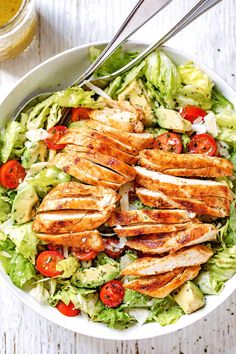 a salad with chicken, lettuce and tomatoes