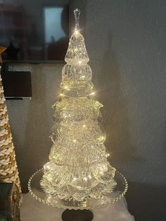 a lighted glass christmas tree sitting on top of a table