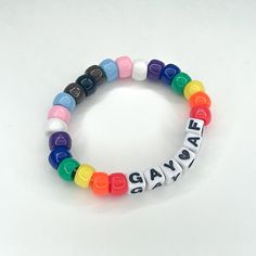 a bracelet with the word gay written on it and multicolored beads in different colors