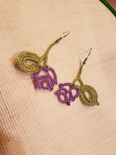 two crocheted earrings are sitting on a piece of fabric