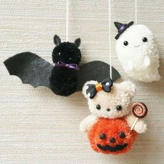 three stuffed animals hanging from strings with bats and pumpkins attached to them, all decorated in different colors