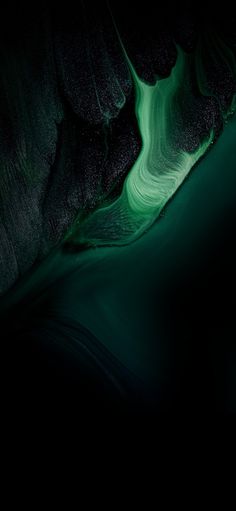 an aerial view of the water and rocks at night with green light coming from above