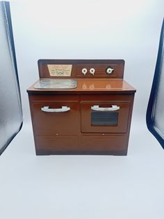 an old fashioned stove sitting in front of two shiny metal chairs on a white background