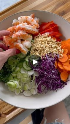 a person holding a bowl full of chopped vegetables and shrimp, with the words raw on it