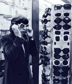 a man talking on a cell phone while standing in front of a display of sunglasses