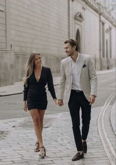 a man and woman walking down the street holding hands