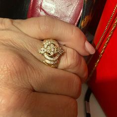 a woman's hand with a gold ring on it and a red box in the background