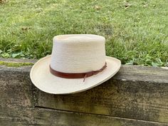 "Upgrade your favorite hat with a custom and customizable leather hat band. Perfectly adjustable to fit any size hat and can be secured in multiple ways to customize your style. Each hat band is handmade from substantial and durable full-grain vegetable tanned leather. Made to your order, the leather is cut, dyed, and finished. The edges are then beveled, burnished, and sealed for a smooth feel. Bands are 5/8\" wide. Sizes are based on the length of the wide part of the leather and can fit a ran Adjustable Brown Boater Hat With Flat Crown, Country Style Adjustable Hat Band For Brimmed Hats, Classic Adjustable Boater Hat For Country Events, Adjustable Flat Crown Hats For Kentucky Derby, Adjustable Natural Color Fedora With Flat Crown, Adjustable Natural Fedora With Flat Crown, Natural Fedora With Adjustable Flat Crown, Adjustable Straw Hat With Flat Crown For Country Events, Country Style Adjustable Fedora With Flat Crown