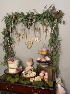 a table topped with cakes and cupcakes next to a sign that says mya