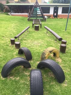 several tires are laying on the grass in front of a playground