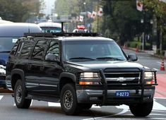 a black truck driving down a street next to other cars