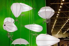 several white lamps hanging from the ceiling in front of a green wall with lights on it