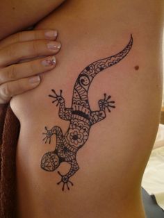 a lizard tattoo on the side of a woman's stomach, with an intricate design