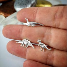 "Solid Fine Silver Dinosaur Earrings, Dinosaur Studs, Stegosaurus, Apatosaurus, Brontosaurus, TRex, Dino Jewelry, Kitsch Jewelry, Stud WHAT IT IS AND WHY YOU WANT IT: Life is short. Don't take it too seriously! Play in the fountain! Eat too much ice cream! Wear something fun that doesn't scream \"I'm an adult\". Dinosaurs are not just for kids anymore! Choose a pair of matching earrings, a single earring of each style (1 T-Rex, 1 Stegosaurus, and 1 Brontosaurus), or get a pair of all 3 styles! Y Earrings Dinosaur, Dinosaur Jewelry, Tiny Dinosaur, Dinosaur Earrings, Earring Silver, Mismatched Earrings, Unusual Jewelry, Funky Jewelry, Agate Jewelry